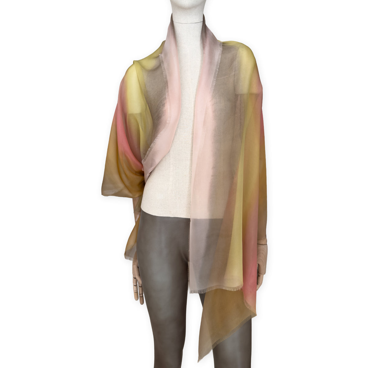 Mannequin wearing a hand-painted Otta pure silk scarf on a white background in 
pink, yellow and brown tones. soft, fresh and lightweight, and elegant accessory measuring 65 x 175 cm. Unique artisan scarf with hand-fringed edges, perfect for women and men.
