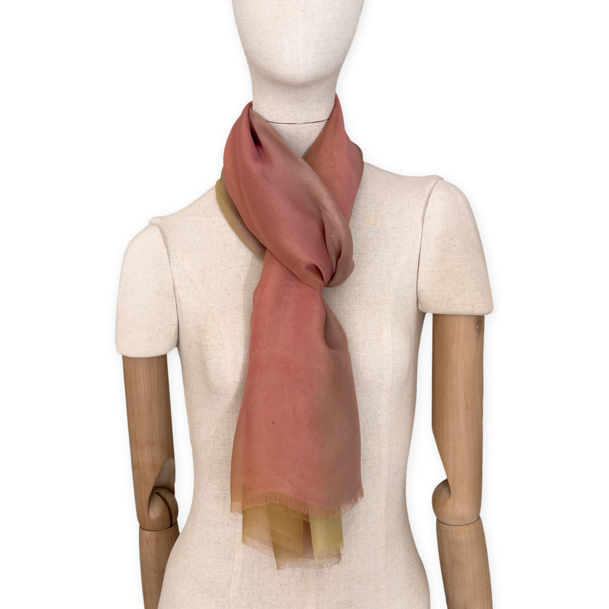 Mannequin wearing a hand-painted Otta pure silk scarf on a white background in 
pink, yellow and brown tones. soft, fresh and lightweight, and elegant accessory measuring 65 x 175 cm. Unique artisan scarf with hand-fringed edges, perfect for women and men.
