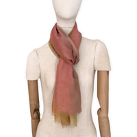 Mannequin wearing a hand-painted Otta pure silk scarf on a white background in 
pink, yellow and brown tones. soft, fresh and lightweight, and elegant accessory measuring 65 x 175 cm. Unique artisan scarf with hand-fringed edges, perfect for women and men.
