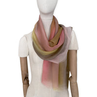 Mannequin wearing a hand-painted Otta pure silk scarf on a white background in 
pink, yellow and brown tones. soft, fresh and lightweight, and elegant accessory measuring 65 x 175 cm. Unique artisan scarf with hand-fringed edges, perfect for women and men.
