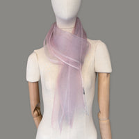 Mannequin wearing a hand-painted Otta silk scarf on a gray background in 
pink and light gray tones. Lightweight, soft, and elegant accessory measuring 50 x 200 cm. Unique artisan scarf with hand-fringed edges, perfect for women and men.
