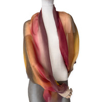 Mannequin wearing a colorful and lightweight silk scarf on a white background. Silk scarf is in shades of red, orange, yellow and brown colors. It is hand-painted scarf in measures 176 x 64 cm by otta-italy scarves brand.

