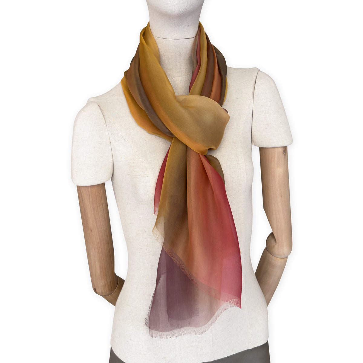 Mannequin wearing a colorful and lightweight silk scarf on a white background. Silk scarf is in shades of red, orange, yellow and brown colors. It is hand-painted scarf in measures 176 x 64 cm by otta-italy scarves brand.


