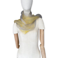Mannequin wearing a colorful and lightweight silk scarf on a white background. Silk scarf is in shades of yellow and gray colors. It is hand-painted scarf in measures 50 x 194 cm by otta-italy scarves brand.
