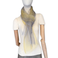 Mannequin wearing a colorful and lightweight silk scarf on a white background. Silk scarf is in shades of yellow and gray colors. It is hand-painted scarf in measures 50 x 194 cm by otta-italy scarves brand.
