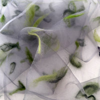 Close-up of a hand-painted Otta-Italy silk organza scarf showcasing rich shades of green hand-needle wool felting over a sheer gray background.