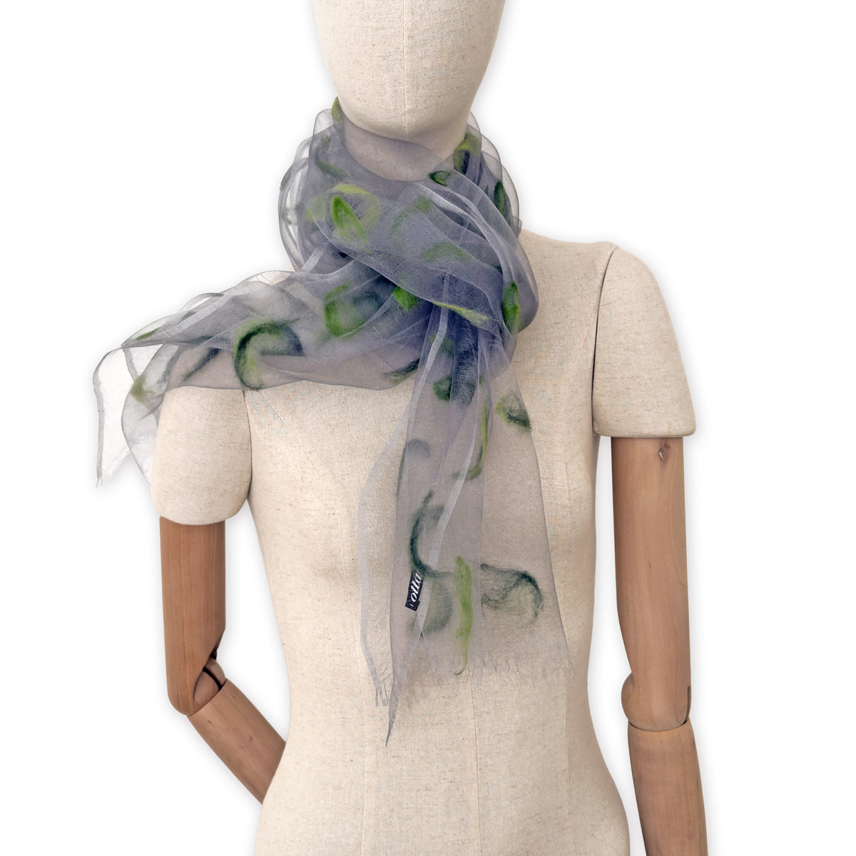 Mannequin wearing an elegant hand-painted Otta-Italy organic silk and wool felted scarf on a white background. Gray and green tones.