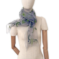 Mannequin wearing an elegant hand-painted Otta-Italy organic silk and wool felted scarf on a white background. Gray and green tones.