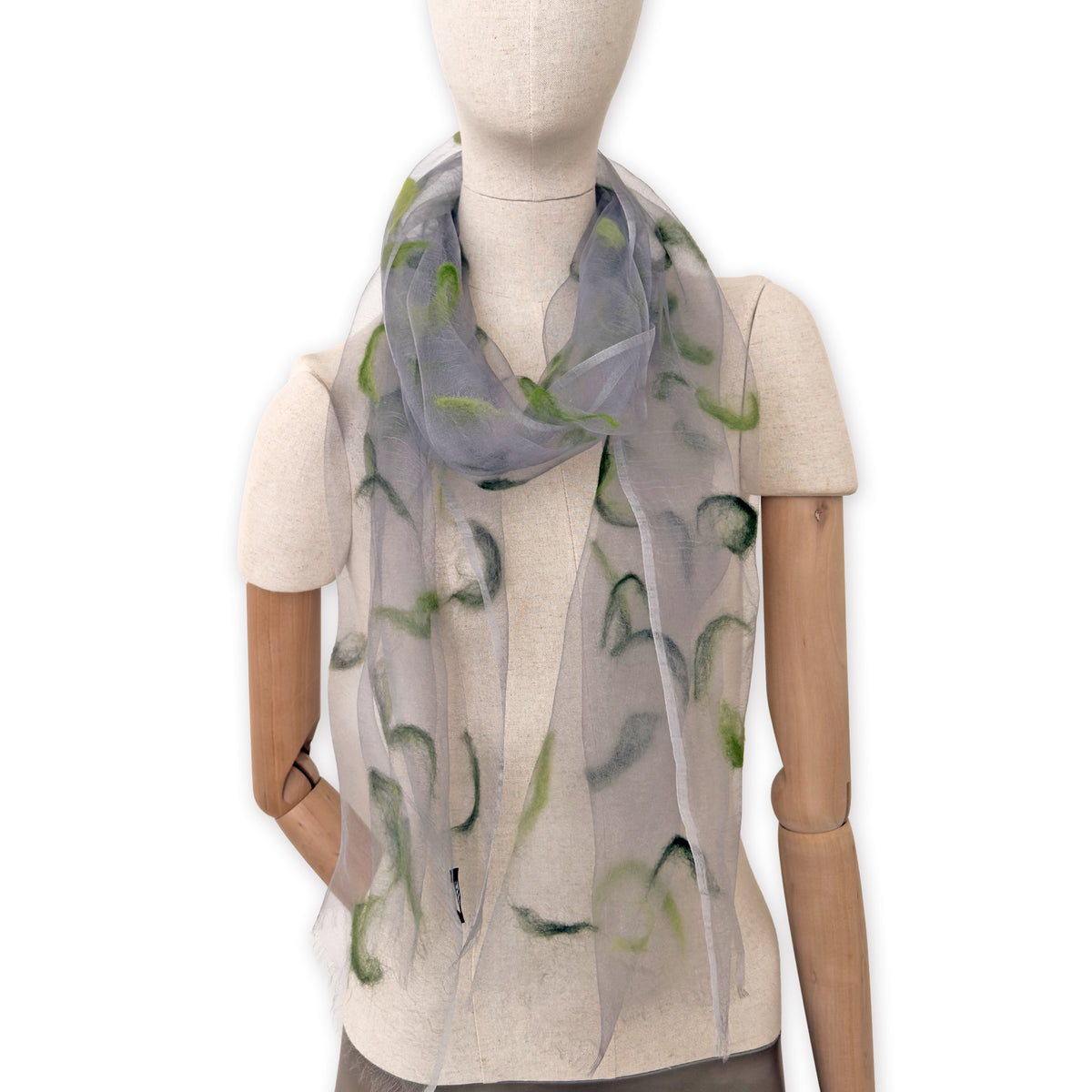 Mannequin wearing an elegant hand-painted Otta-Italy organic silk and wool felted scarf on a white background. Gray and green tones.