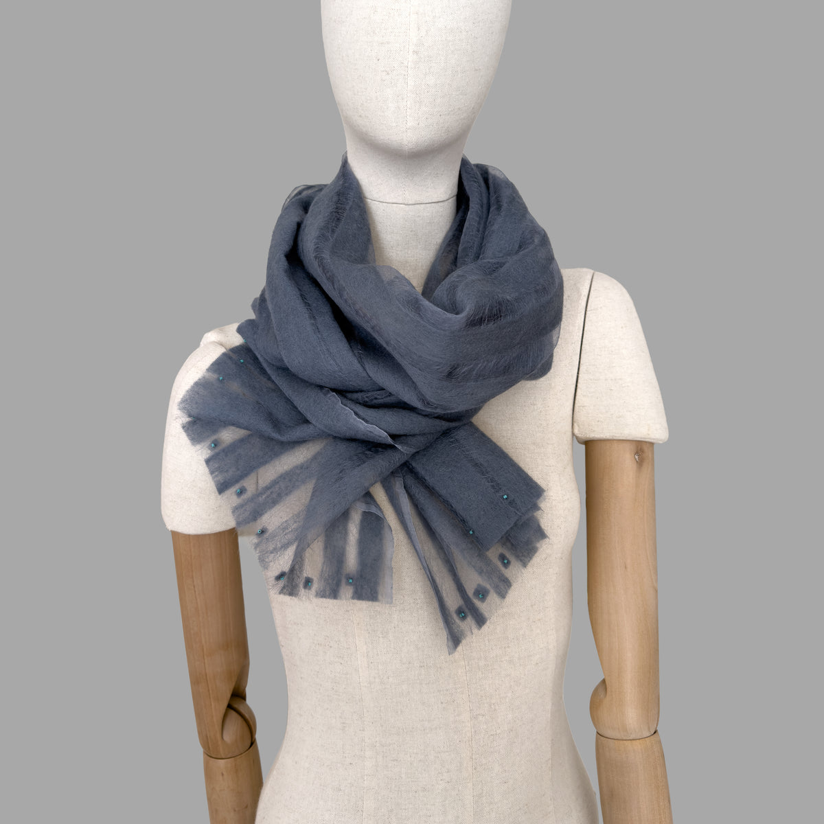 Mannequin wearing scarf on a beige background. Hand-painted silk scarf with hand-needle felted wool by Otta-Italy, 40 x 176 cm, featuring 
gray. Luxury Italian pure silk accessory, soft, fresh and lightweight scarf for women and men.
