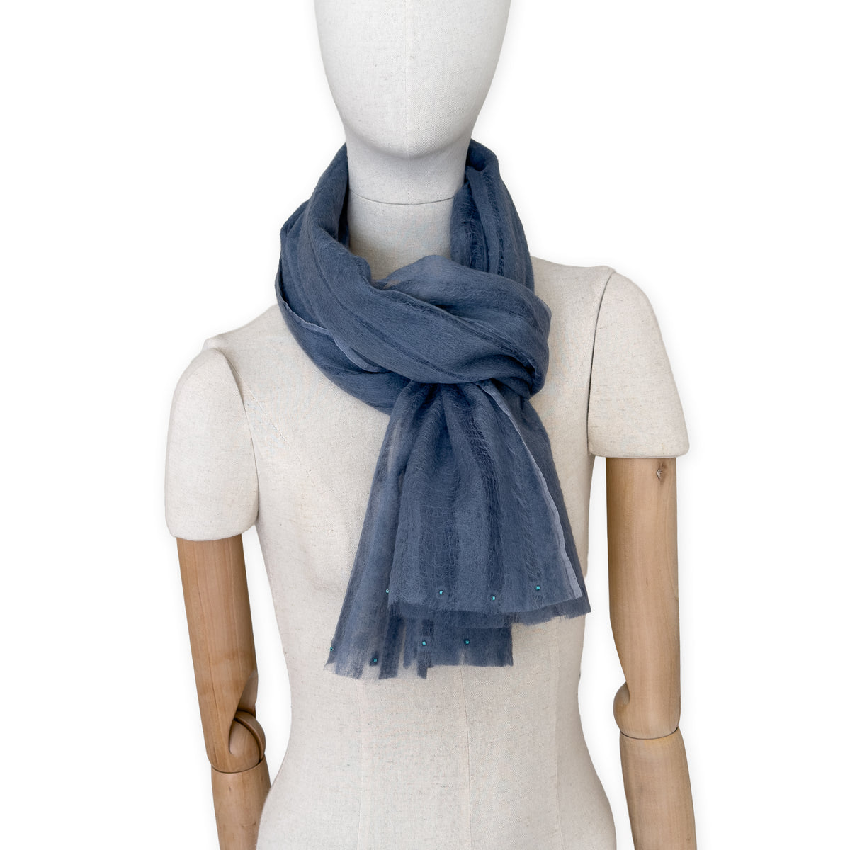 Mannequin wearing a hand-painted Otta pure silk with hand-needle felted wool scarf on a white background in 
gray tones. soft, fresh and lightweight, and elegant accessory measuring 40 x 176 cm. Unique artisan scarf with hand-fringed edges, perfect for women and men.
