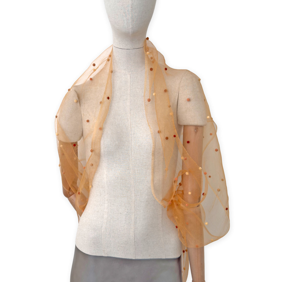 Mannequin wearing a hand-painted Otta pure silk with hand-needle felted wool scarf on a white background in 
orange, peach, beige and brown tones. soft, fresh and lightweight, and elegant accessory measuring 183 x 44 cm. Unique artisan scarf with hand-fringed edges, perfect for women and men.
