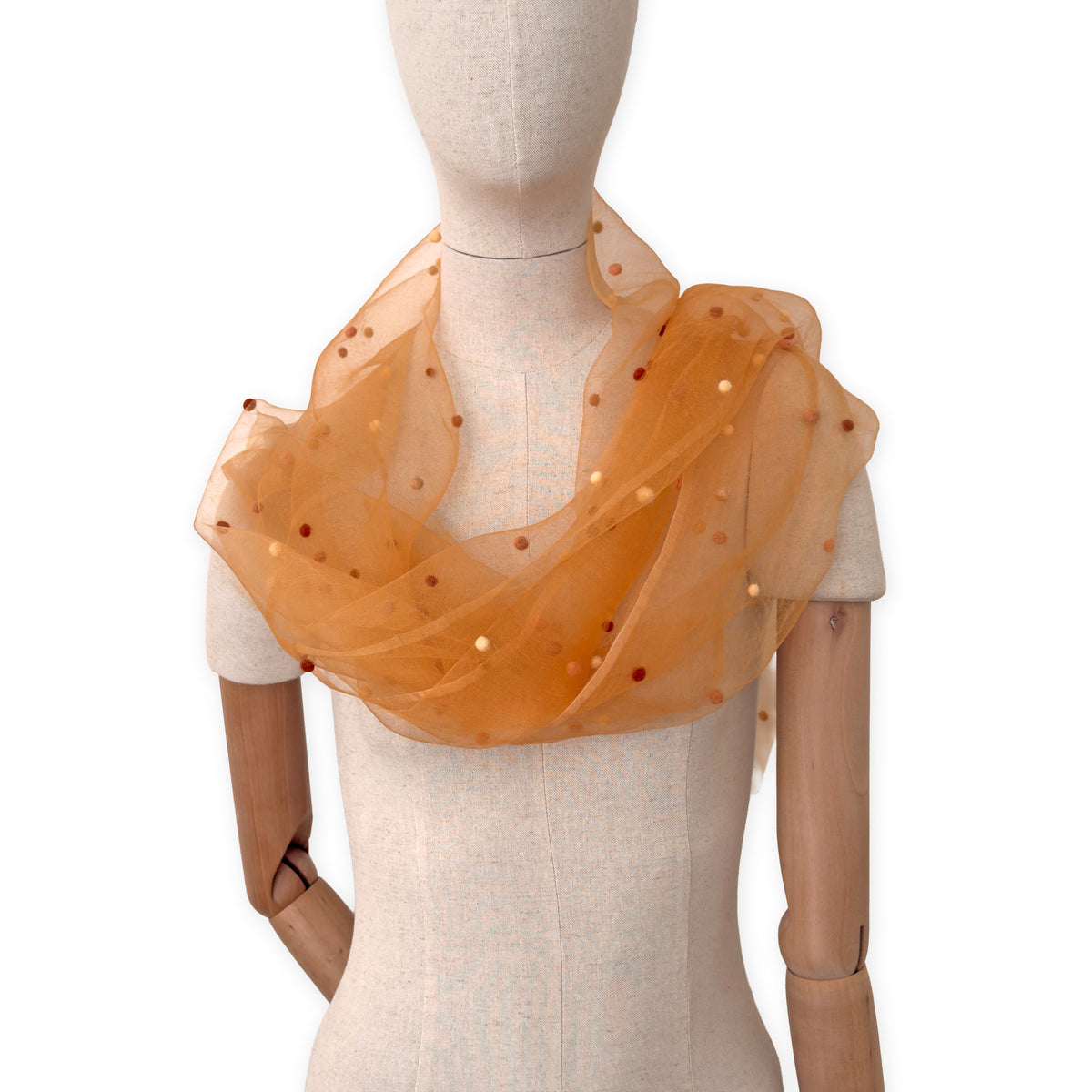 Mannequin wearing a hand-painted Otta pure silk with hand-needle felted wool scarf on a white background in 
orange, peach, beige and brown tones. soft, fresh and lightweight, and elegant accessory measuring 183 x 44 cm. Unique artisan scarf with hand-fringed edges, perfect for women and men.
