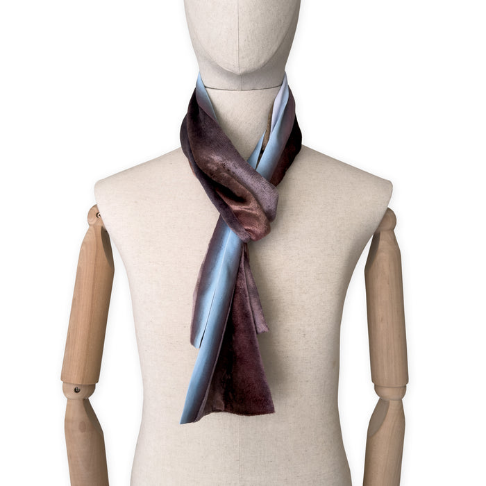 Mannequin wearing a colorful velvet scarf on a white background. Velvet scarf is in shades of brown and blue colors. It is hand-painted scarf in measures 180 x 18 cm by otta-italy scarves brand.
