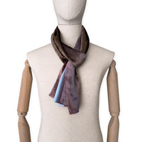 Mannequin wearing a colorful velvet scarf on a white background. Velvet scarf is in shades of brown and blue colors. It is hand-painted scarf in measures 180 x 18 cm by otta-italy scarves brand.

