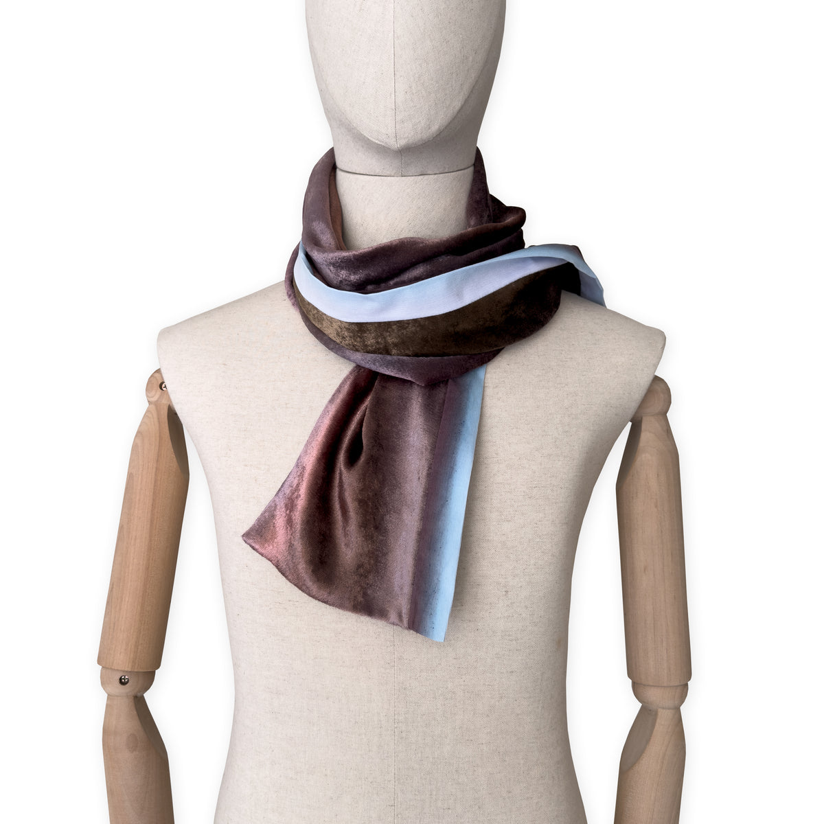 Mannequin wearing a colorful velvet scarf on a white background. Velvet scarf is in shades of brown and blue colors. It is hand-painted scarf in measures 180 x 18 cm by otta-italy scarves brand.
