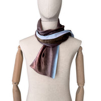 Mannequin wearing a colorful velvet scarf on a white background. Velvet scarf is in shades of brown and blue colors. It is hand-painted scarf in measures 180 x 18 cm by otta-italy scarves brand.
