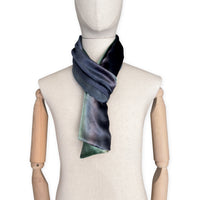 Mannequin wearing a colorful velvet scarf on a white background. Velvet scarf is in shades of green, beige and blue navy colors. It is hand-painted scarf in measures 182 x 18 cm by otta-italy scarves brand.
