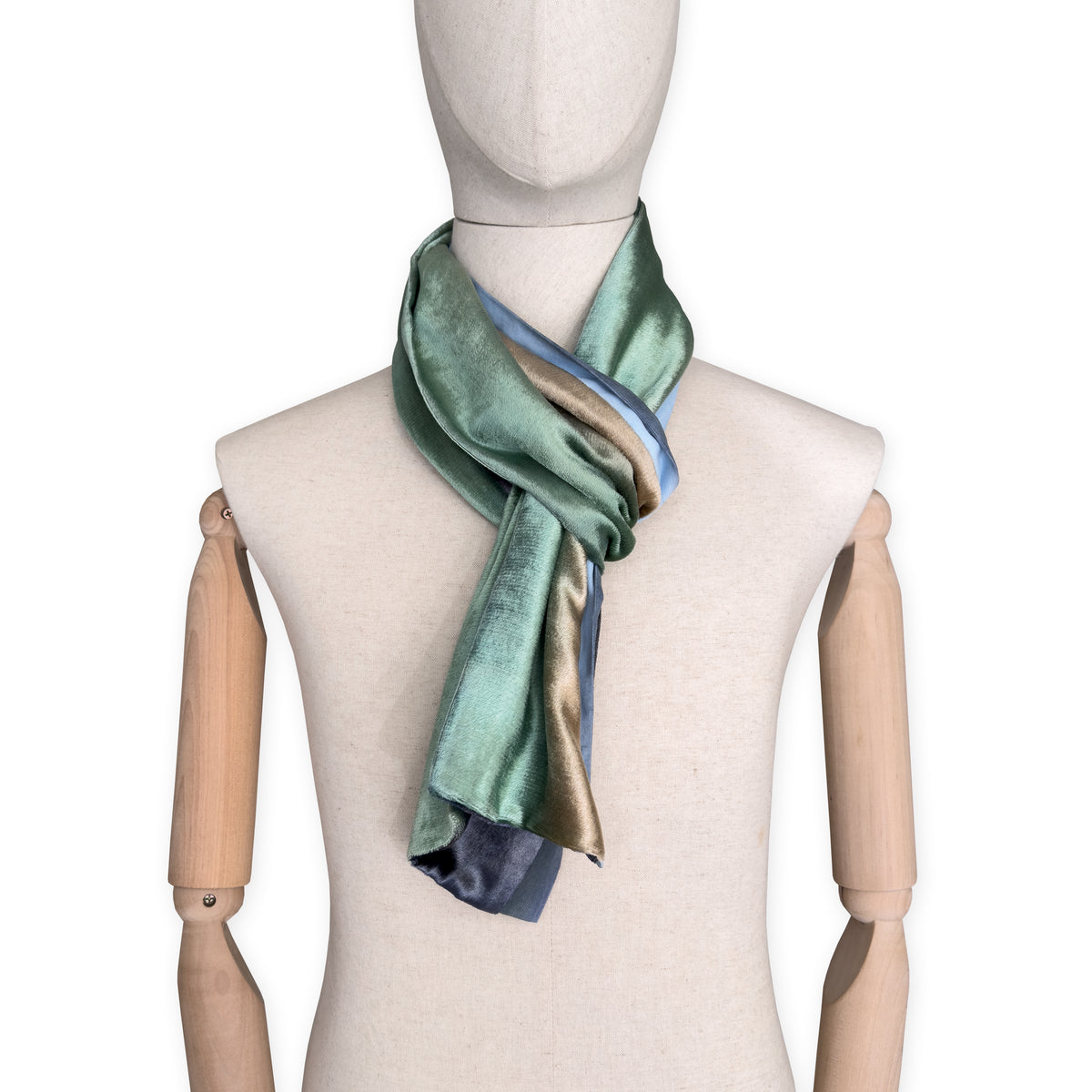 Mannequin wearing a colorful velvet scarf on a white background. Velvet scarf is in shades of green, beige and blue navy colors. It is hand-painted scarf in measures 182 x 18 cm by otta-italy scarves brand.
