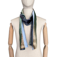 Mannequin wearing a colorful velvet scarf on a white background. Velvet scarf is in shades of green, beige and blue navy colors. It is hand-painted scarf in measures 182 x 18 cm by otta-italy scarves brand.
