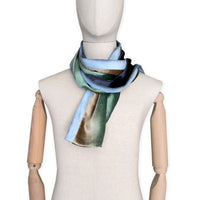 Mannequin wearing a colorful velvet scarf on a white background. Velvet scarf is in shades of green, beige and blue navy colors. It is hand-painted scarf in measures 182 x 18 cm by otta-italy scarves brand.
