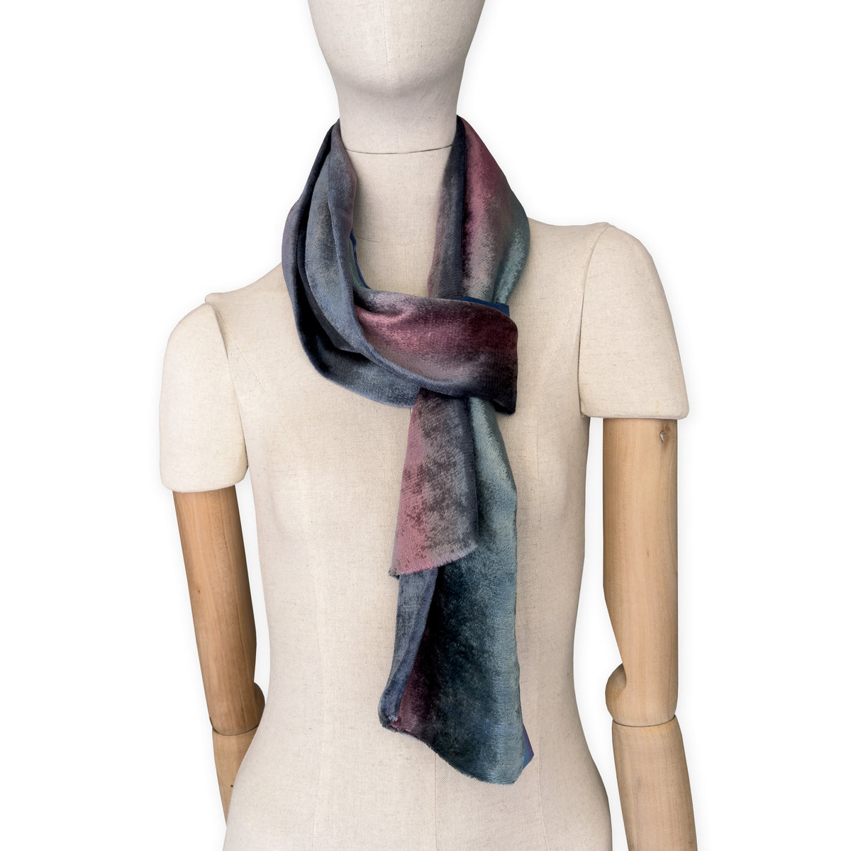 Mannequin wearing a colorful velvet scarf on a white background. Velvet scarf is in shades of green, pink and blue navy colors. It is hand-painted scarf in measures 180 x 20 cm by otta-italy scarves brand.
