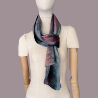 Mannequin wearing a colorful velvet scarf on a gray background. Velvet scarf is in shades of green, pink and blue navy colors. It is hand-painted scarf in measures 180 x 20 cm by otta-italy scarves brand.