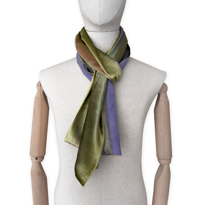 Mannequin wearing a colorful velvet scarf on a white background. Velvet scarf is in shades of green, pink and purple colors. It is hand-painted scarf in measures 185 x 20 cm by otta-italy scarves brand.
