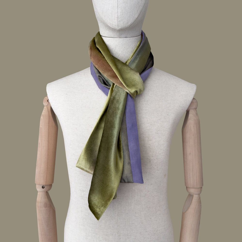 Mannequin wearing a hand-painted velvet scarf by Otta-Italy, gray background. Green, pink and purple shades. 185x20 cm.