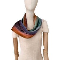 Mannequin wearing a colorful velvet scarf on a white background. Velvet scarf is in shades of green, red and purple colors. It is hand-painted scarf in measures 181 x 18 cm by otta-italy scarves brand.
