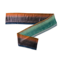 Colorful velvet scarf in green, red and purple shades on a white background. t is hand-painted scarf in measures 181 x 18 cm by otta-italy scarves brand. Luxury Italian velvet accessory, soft and warm scarf for women and men.
