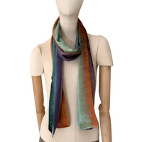 Mannequin wearing a colorful velvet scarf on a white background. Velvet scarf is in shades of green, red and purple colors. It is hand-painted scarf in measures 181 x 18 cm by otta-italy scarves brand.
