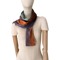 Mannequin wearing a colorful velvet scarf on a white background. Velvet scarf is in shades of green, red and purple colors. It is hand-painted scarf in measures 181 x 18 cm by otta-italy scarves brand.
