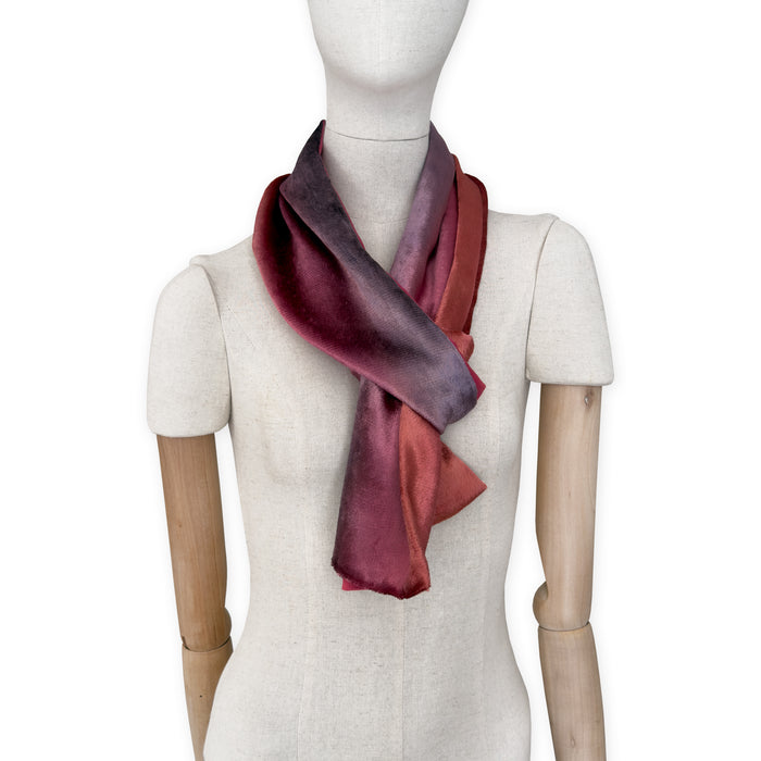 Mannequin wearing a colorful velvet scarf on a white background. Velvet scarf is in shades of red and purple colors. It is hand-painted scarf in measures 184 x 17 cm by otta-italy scarves brand.
