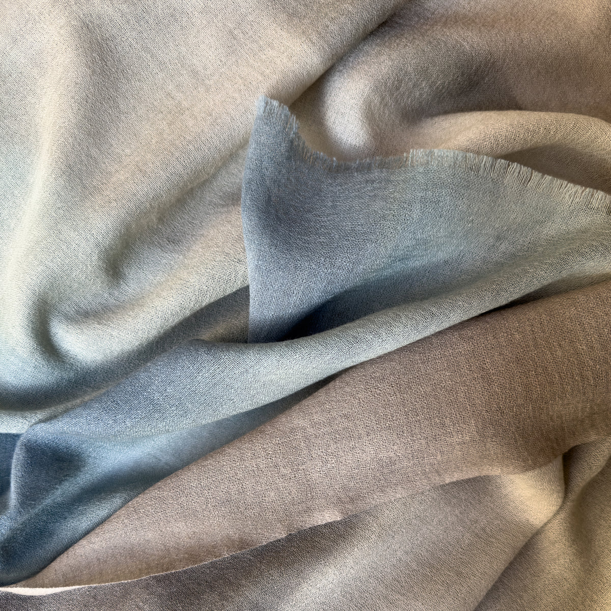Close-up of soft fabric. Hand-painted wool scarf by Otta-Italy, 56 x 177 cm, featuring brown, beige and blue colors. Luxury Italian mix accessory, soft and warm scarf for women and men.
