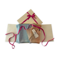Set of scarves in a gift box with a pink ribbon on a white background. 
Hand-painted wool scarf by Otta-Italy, 61 x 197 cm, featuring 
blue, gray and ocher. Luxury Italian pure wool accessory, soft and warm scarf for women and men.
