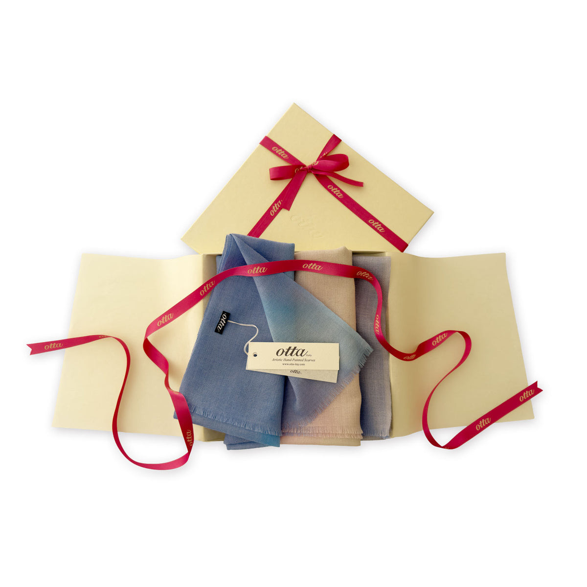 Luxury gift box with a pink ribbon containing a hand-painted Otta pure wool scarf on a white background.
