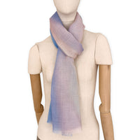 Mannequin wearing an elegant hand-painted Otta pure wool scarf on a white background. Warm blue, pink, beige and gray tones.
