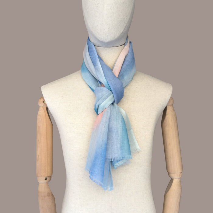 Mannequin wearing scarf on a beige background. Hand-painted wool scarf by Otta-Italy, 61 x 197 cm, featuring 
pastel blue and pink. Luxury Italian pure wool accessory, soft and warm scarf for women and men.
