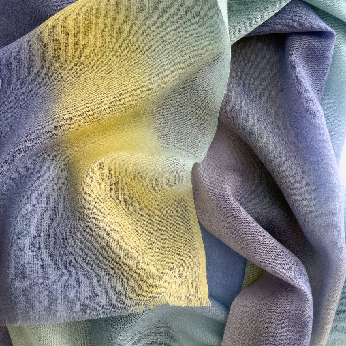 Close-up of soft fabric. Hand-painted wool scarf by Otta-Italy, 57 x 180 cm, featuring blue, purple, yellow colors. Luxury Italian mix accessory, soft and warm scarf for women and men.
