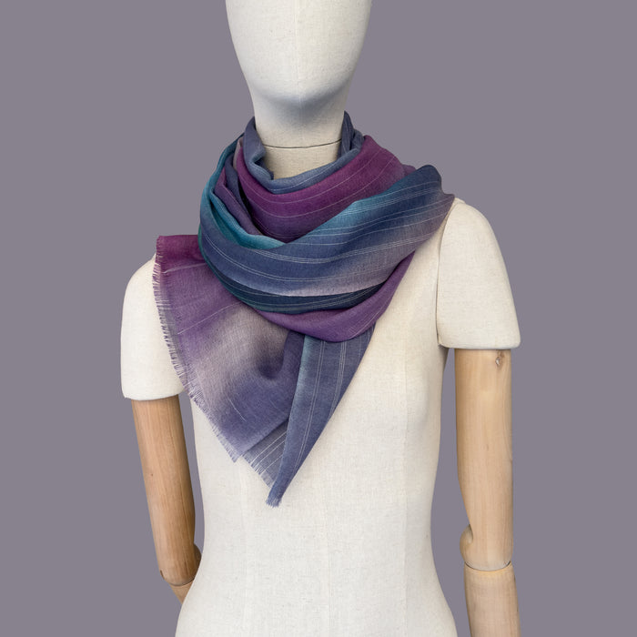 Mannequin wearing scarf on a gray background. Hand-painted wool scarf by Otta-Italy, 61 x 197 cm, featuring 
purple, emerald green and light blue. Luxury Italian pure wool accessory, soft and warm scarf for women and men.
