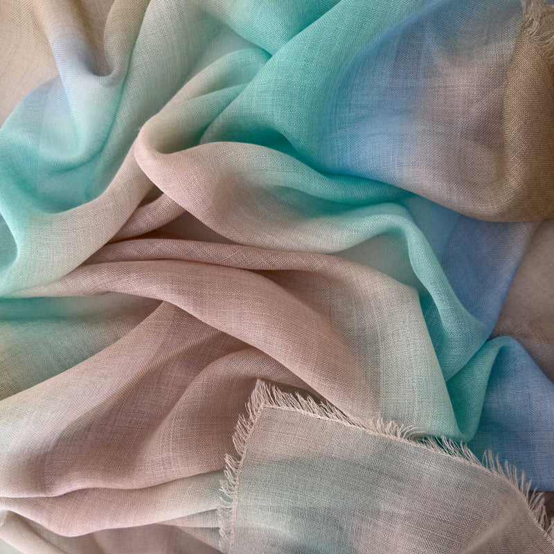 Close-up of hand-painted Otta wool silk blend scarf showcasing soft brown, beige, light blue and turquoise shades with delicate hand-fringed and hand-hemmed edges.
