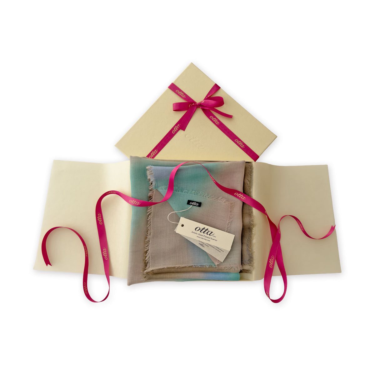 Luxury gift box with a pink ribbon containing a hand-painted Otta wool silk blend scarf on a white background.
