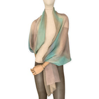 Mannequin wearing an elegant hand-painted Otta wool silk blend scarf on a white background. Warm brown, beige, light blue and turquoise tones.
