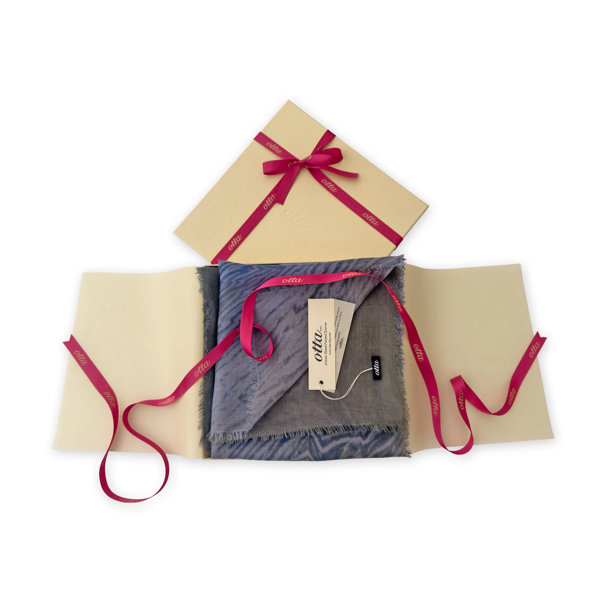 Luxury gift box with a pink ribbon containing a hand-painted Otta wool silk blend scarf on a white background.
