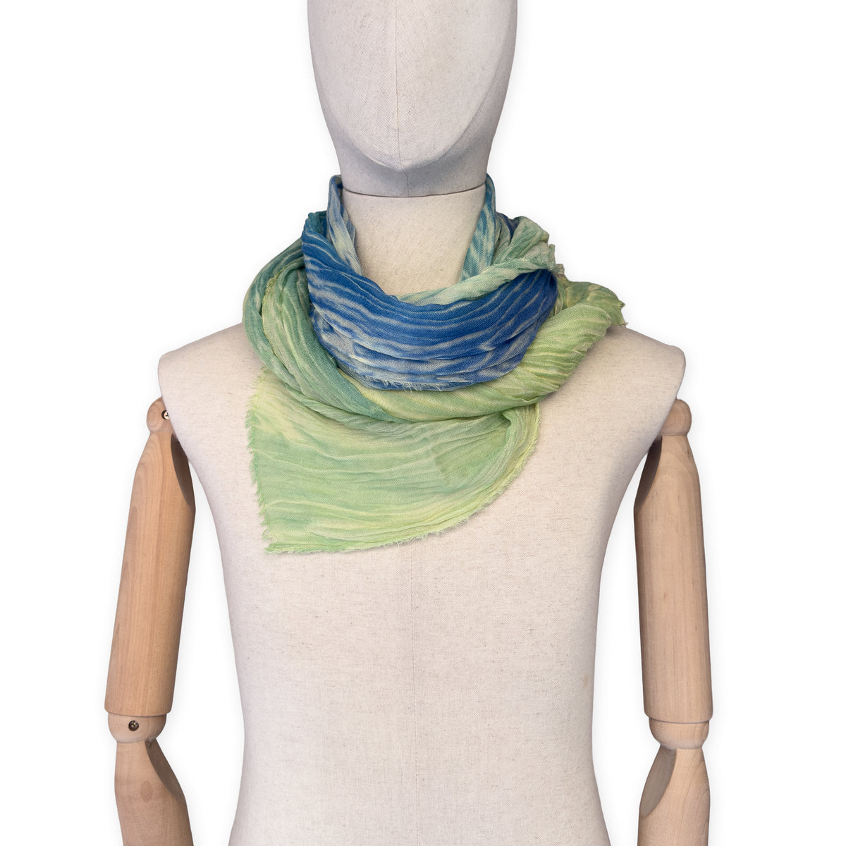 Mannequin wearing scarf on a white background. Hand-painted mix wool and silk scarf by Otta-Italy, 193 x 54 cm, featuring blue, light green and yellow colors. Luxury Italian accessory, soft and warm scarf for women and men.
