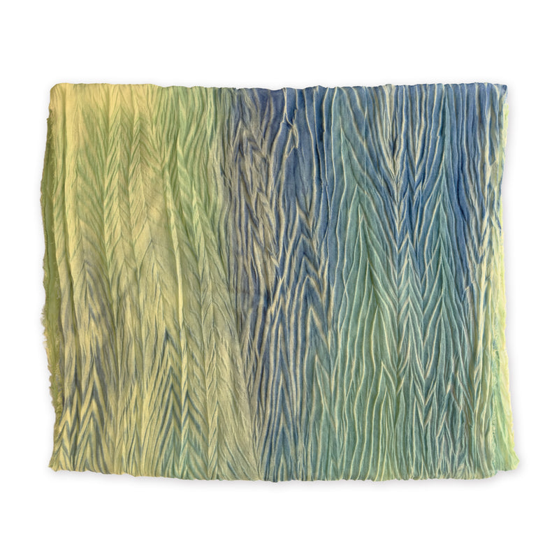 Colorful mix wool and silk scarf in blue, light green and yellow shades on a white background. It is hand-painted scarf in measures 193 x 54 cm by otta-italy scarves brand. Luxury Italian accessory, soft and warm scarf for women and men.
