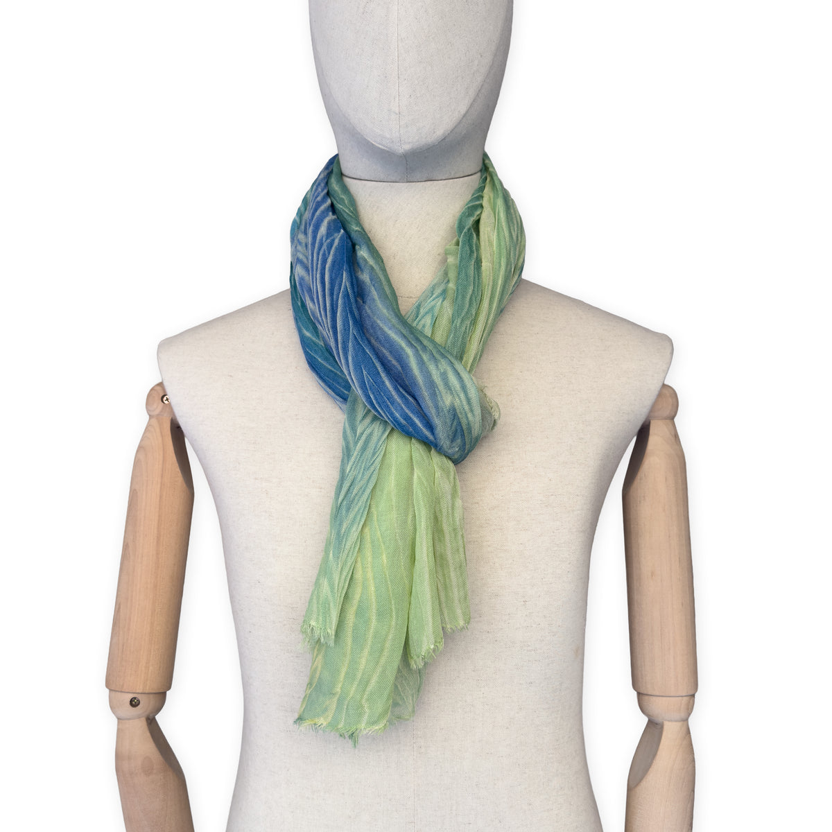 Mannequin wearing scarf on a white background. Hand-painted mix wool and silk scarf by Otta-Italy, 193 x 54 cm, featuring blue, light green and yellow colors. Luxury Italian accessory, soft and warm scarf for women and men.
