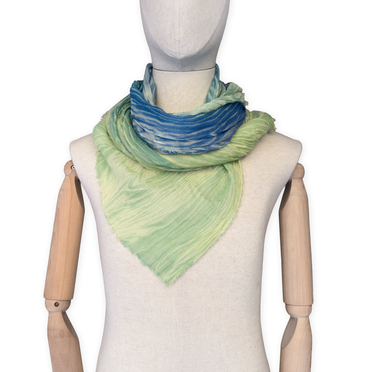 Mannequin wearing scarf on a white background. Hand-painted mix wool and silk scarf by Otta-Italy, 193 x 54 cm, featuring blue, light green and yellow colors. Luxury Italian accessory, soft and warm scarf for women and men.
