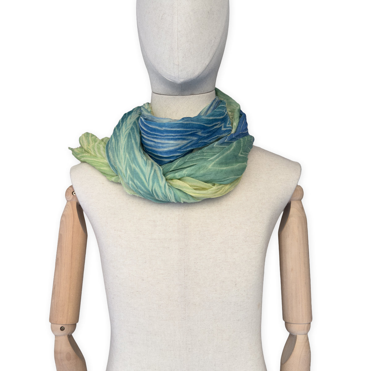 Mannequin wearing scarf on a white background. Hand-painted mix wool and silk scarf by Otta-Italy, 193 x 54 cm, featuring blue, light green and yellow colors. Luxury Italian accessory, soft and warm scarf for women and men.
